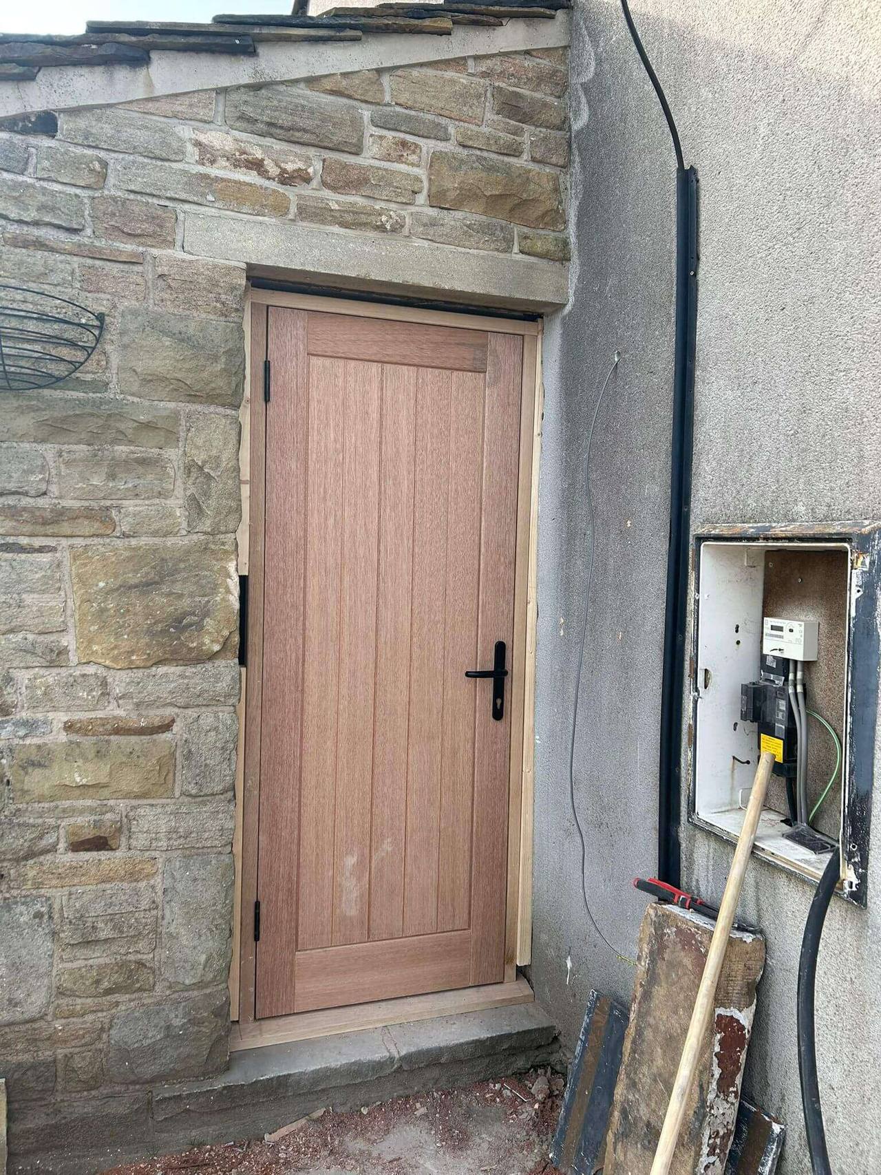 New hardwood cottage-style door fitted into a stone-built wall beneath a stone lintel